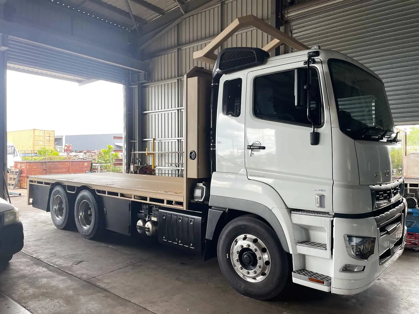 A modified white tray-back truck parked inside a workshop